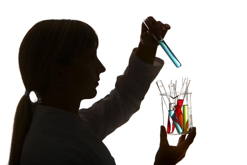 Profile of a lab technician holding various beakers