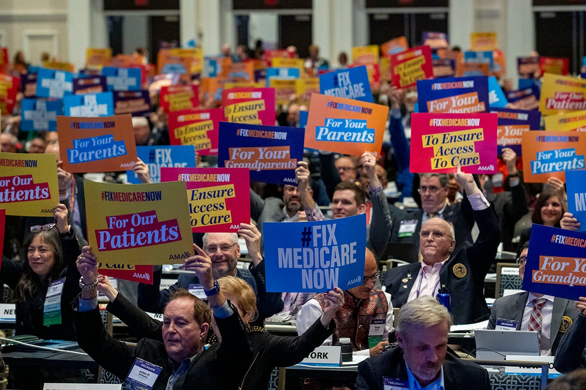 Delegates at the 2023 Interim Meeting of HOD hold "Fix Medicare Now" signs