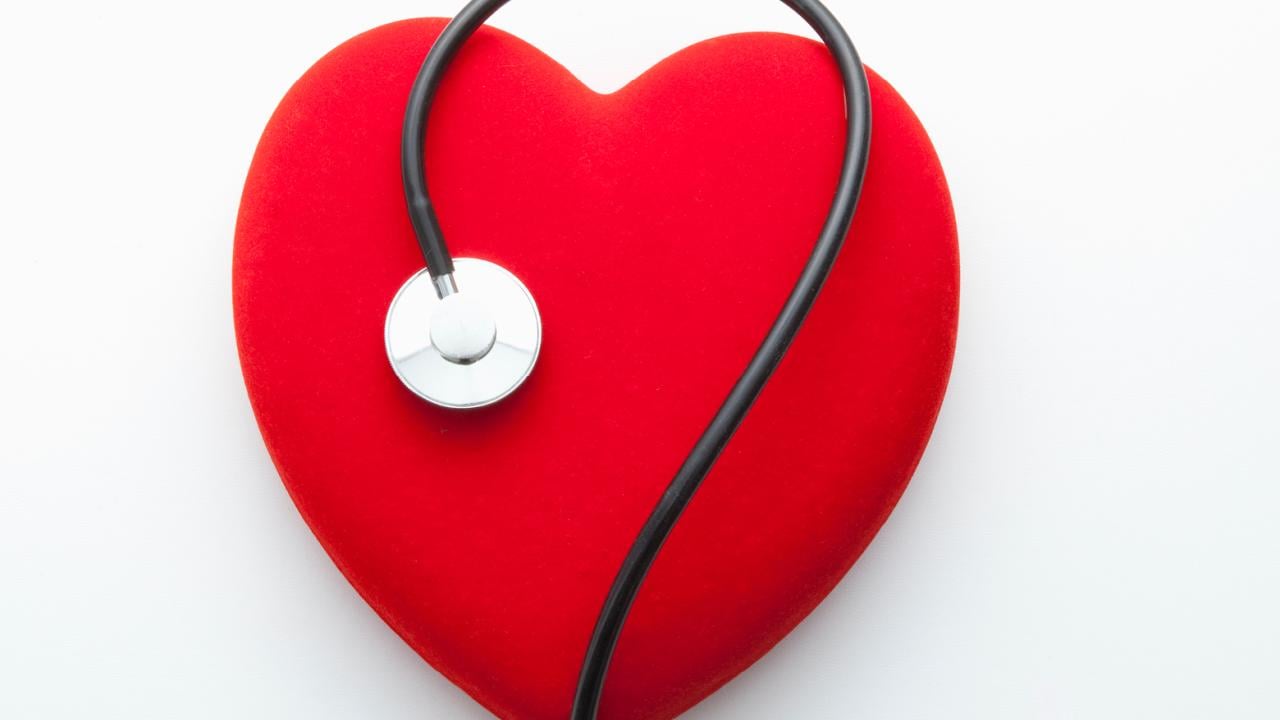 Stethoscope on top of red heart on white background