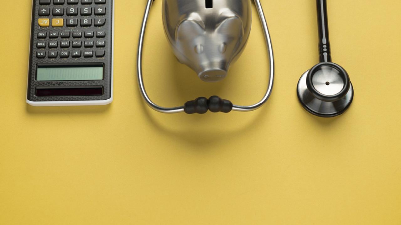 Calculator, stethoscope and piggy bank