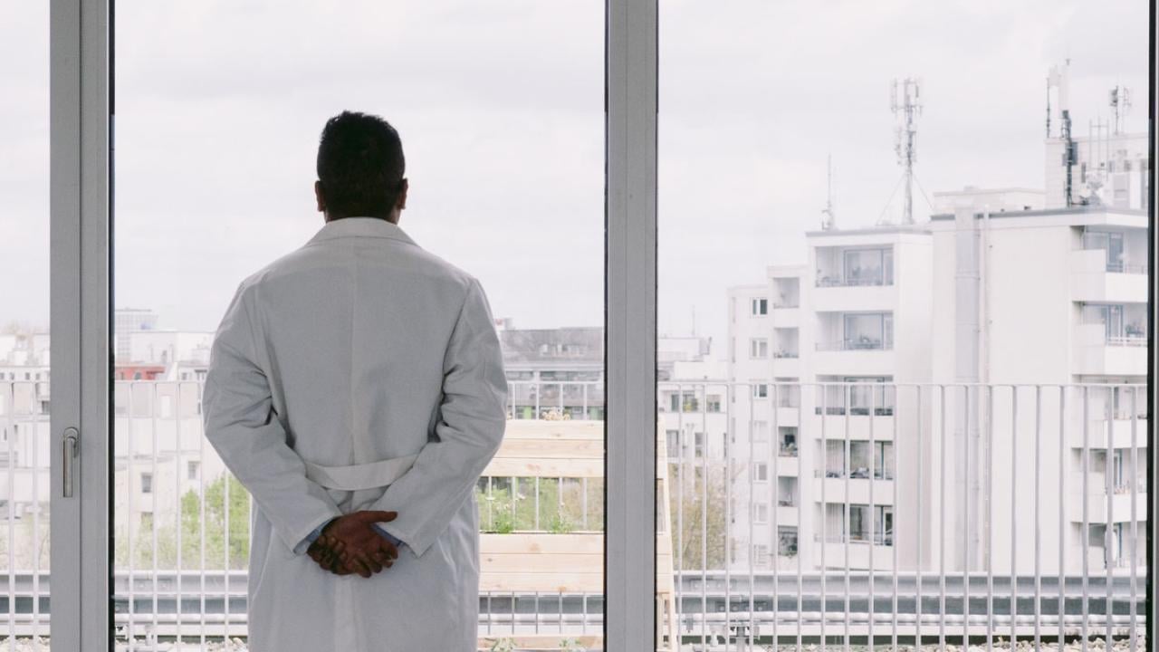 Solitary physician looking out a window