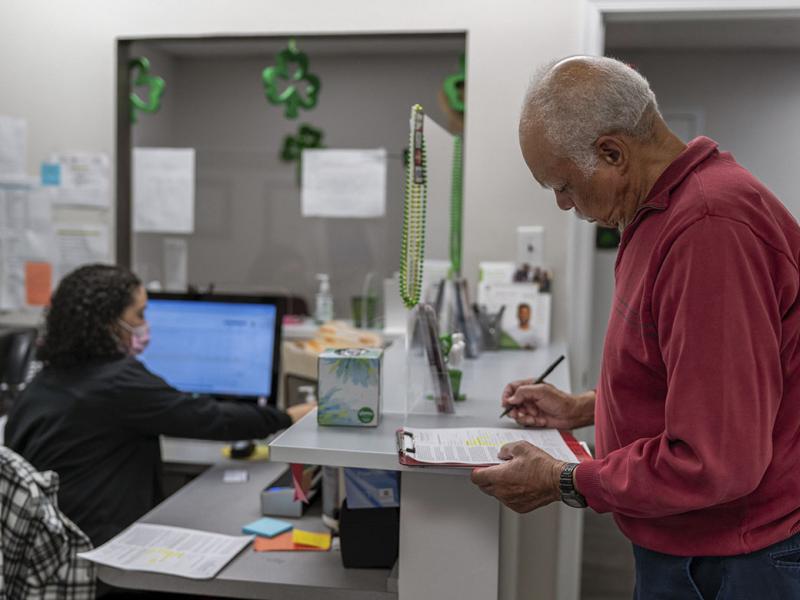 Patient standing at reception desk and completing paperwork at medical appointment
