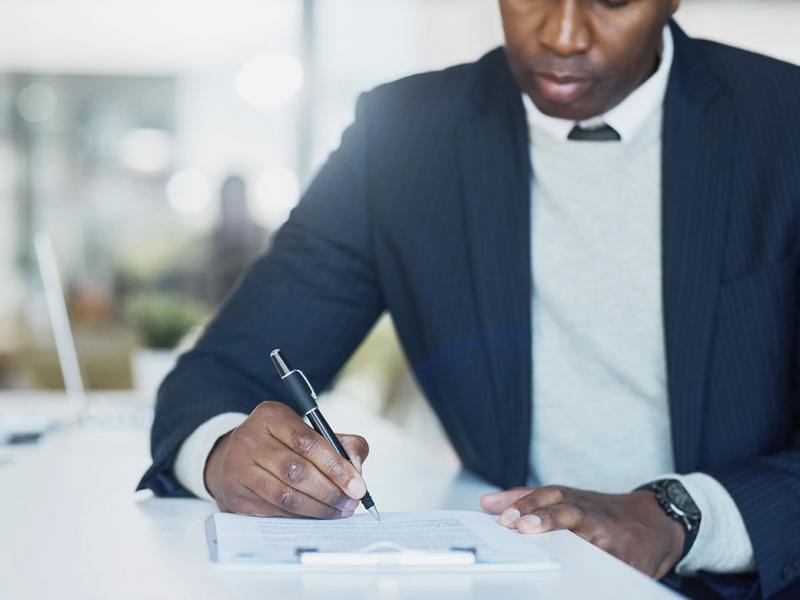 Businessperson filling in paperwork on a clipboard in an office