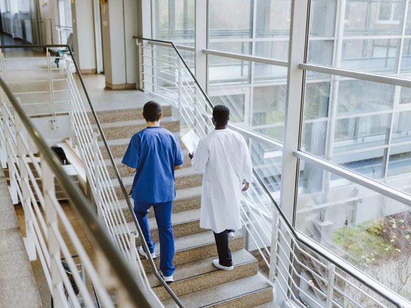 Two health care workers walking up a flight of stairs
