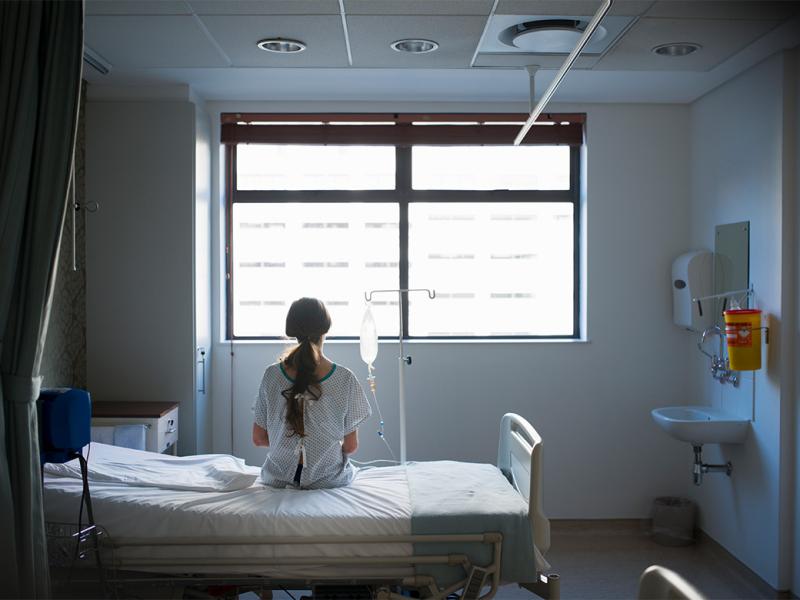 Patient sitting on hospital bed looking out window