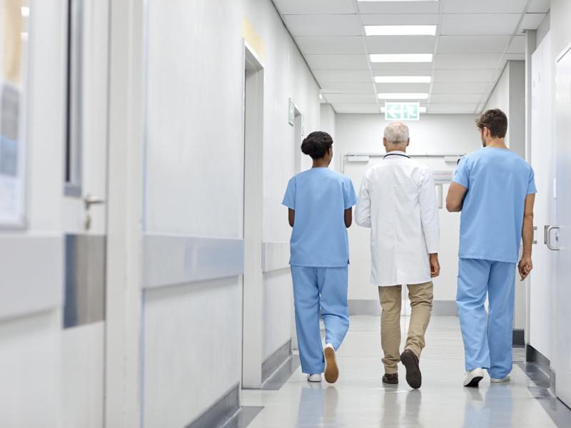 Three health care workers walking down a hallway