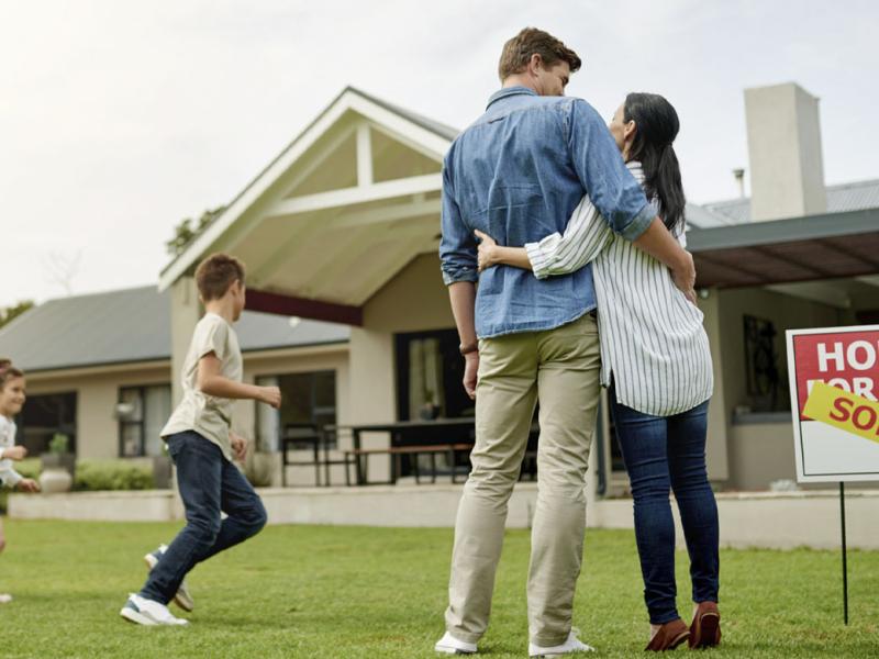 Smiling family in front of a house with a sold sign