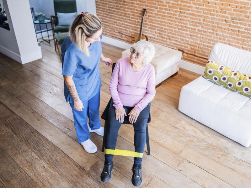 Senior patient and physical therapist doing exercises during house call