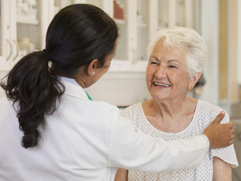 Physician places hand on smiling patient's shoulder