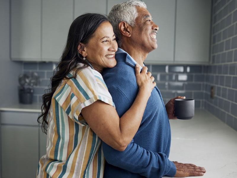 Smiling couple in a kitchen looking out the window