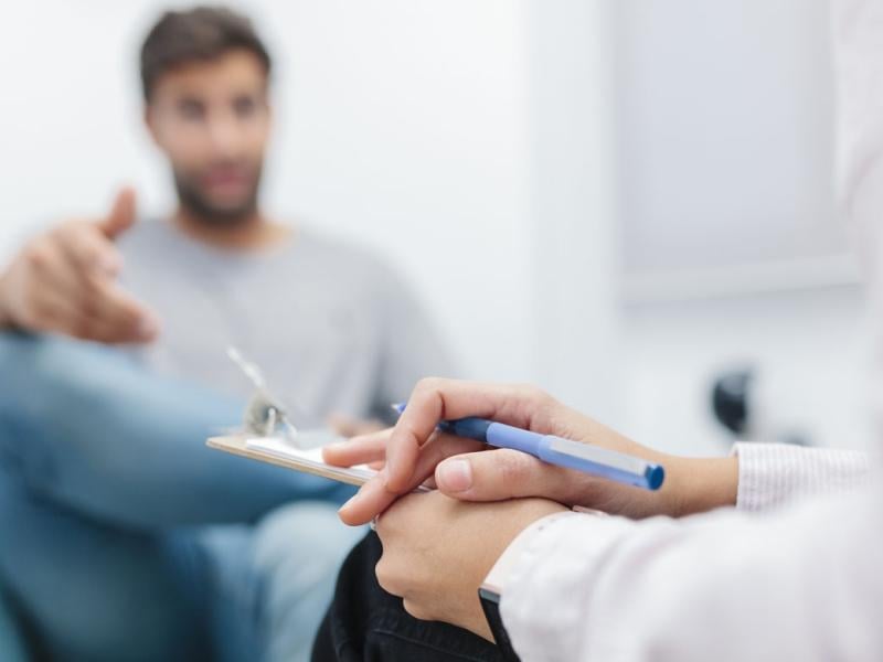 Doctor sitting with note pad while listening to patient