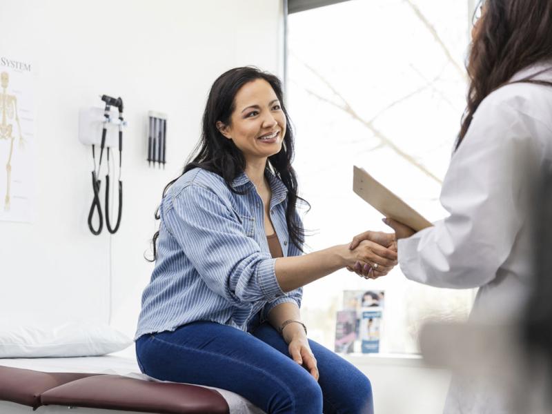 Smiling patient shakes hands with physician