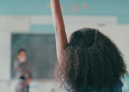 Young person raising their hand in a classroom