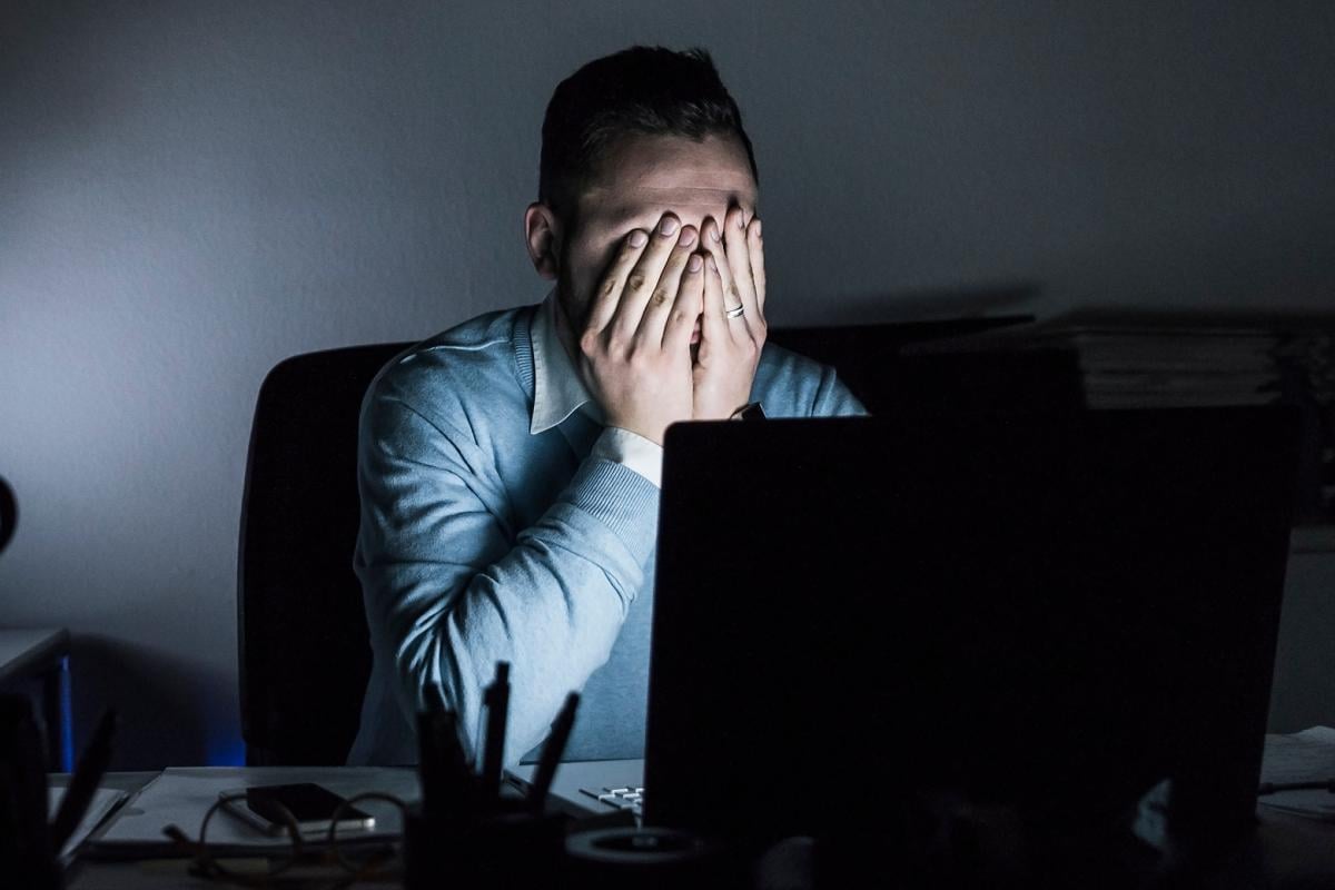 Exhausted man in front of laptop in dark room