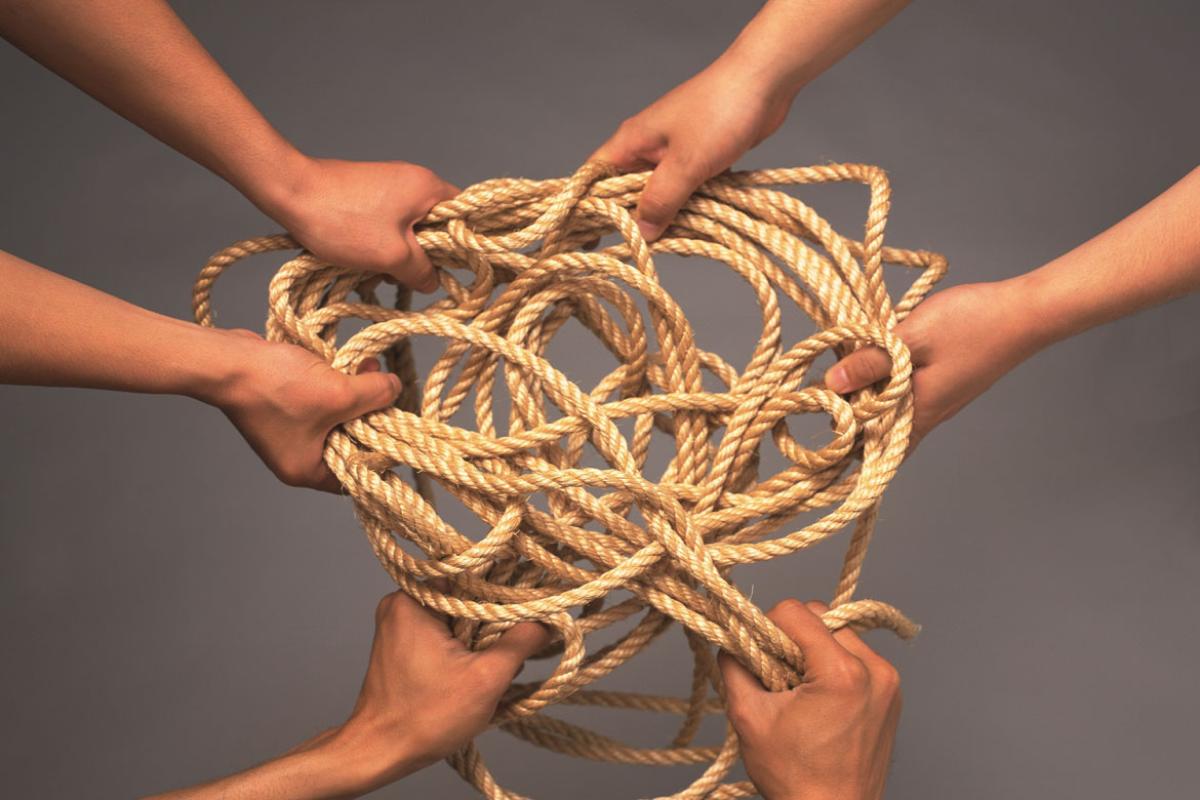 Multiple hands holding a tangled rope