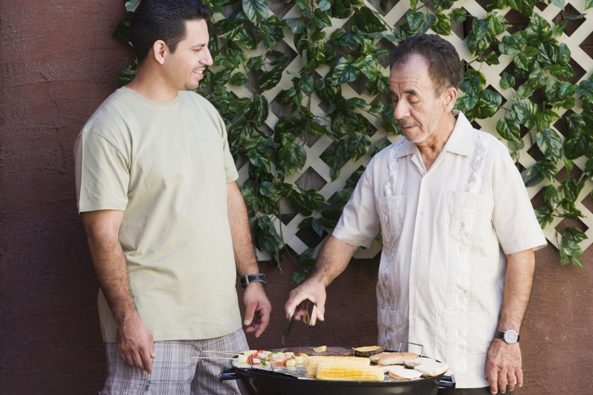 Two men standing at an outdoor grill