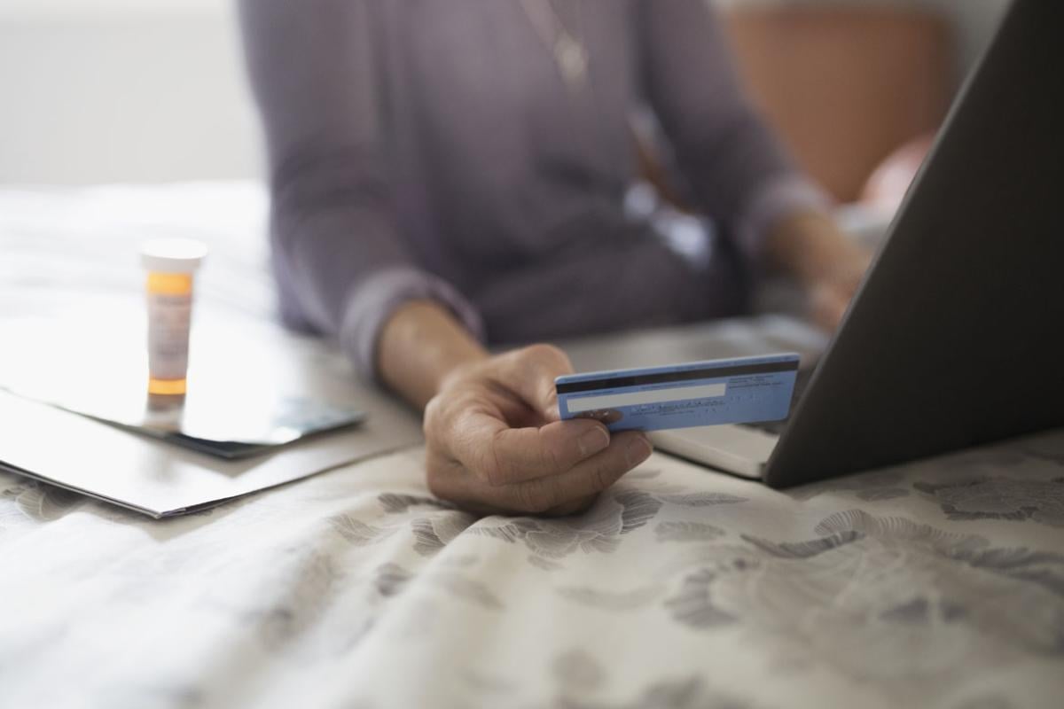 A woman holding a credit card while using a laptop