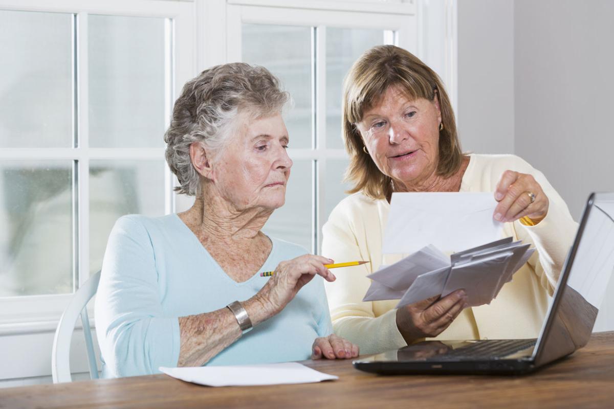 A woman and her mother viewing documents in front of a laptop