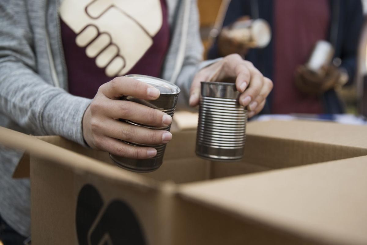 Person putting two tin cans into a box