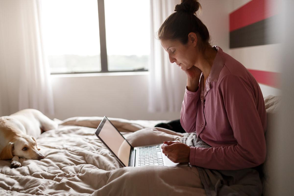 Woman in bed looking at a laptop