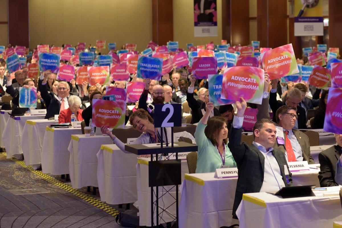 AMA members at 2019 HOD Annual Meeting holding signs with hashtag WomenofAMA