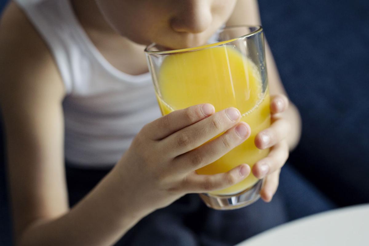 Young child drinking a glass of orange juice