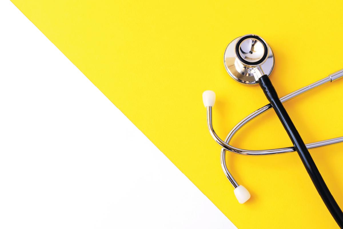 Stethoscope on flat surface with a yellow background