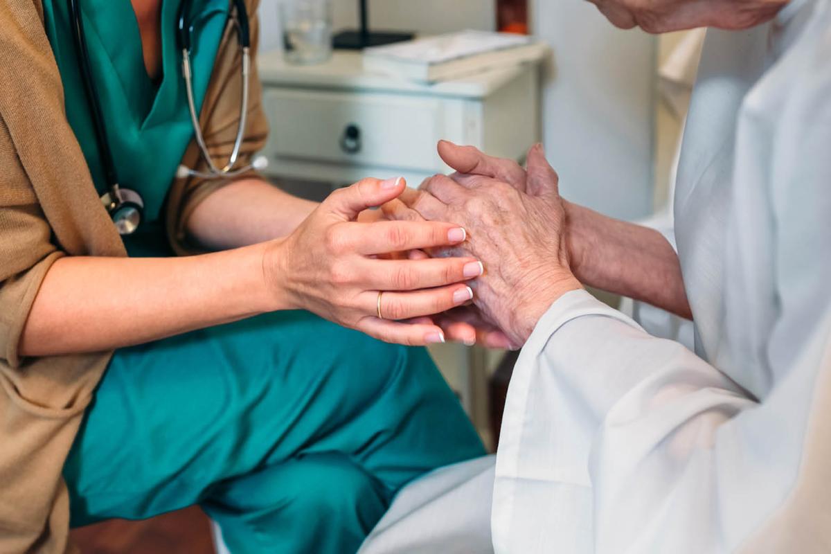Health care professional holding hands with a patient