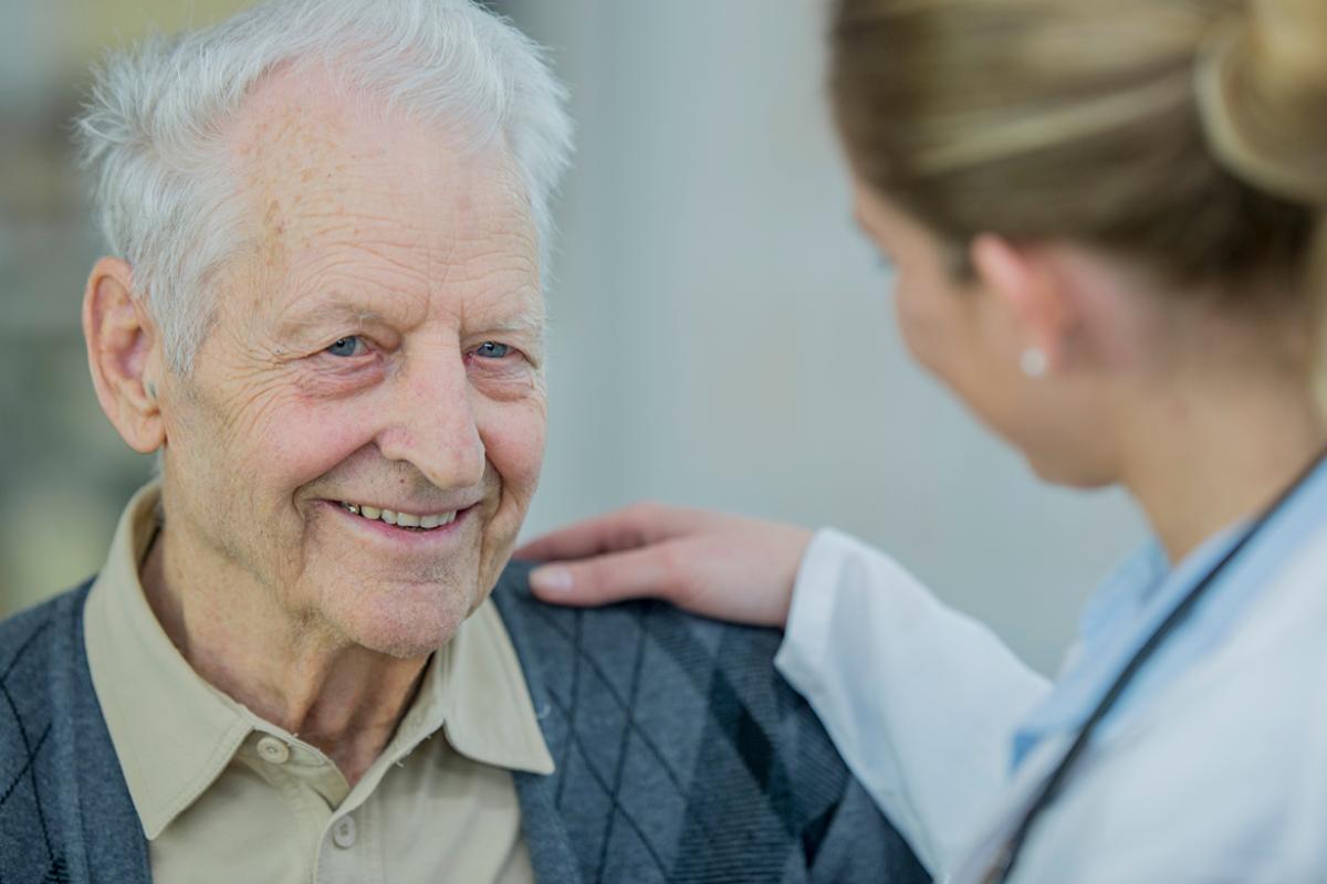 Older man smiling, comforted by doctor