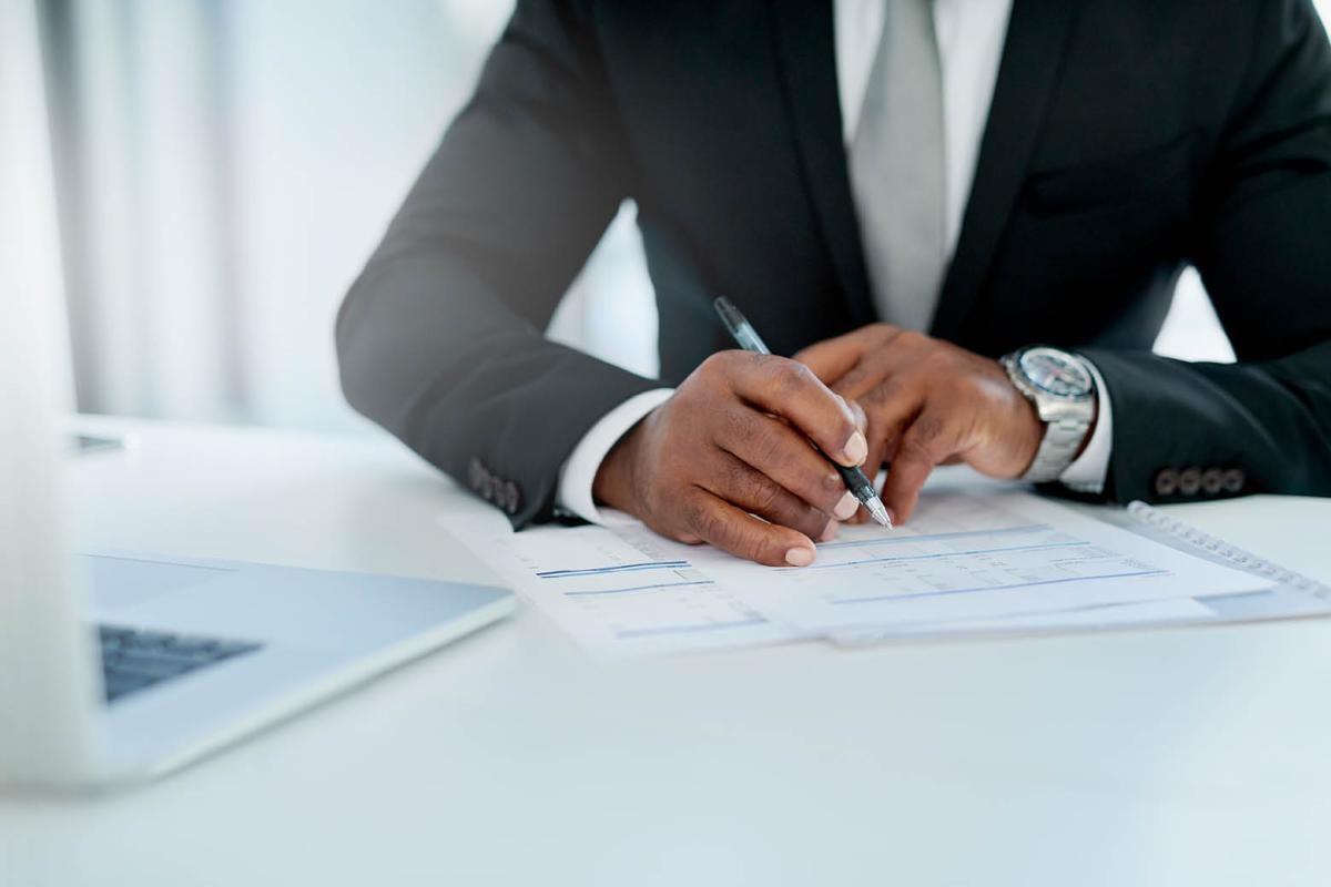 Man in a suit writing on a document