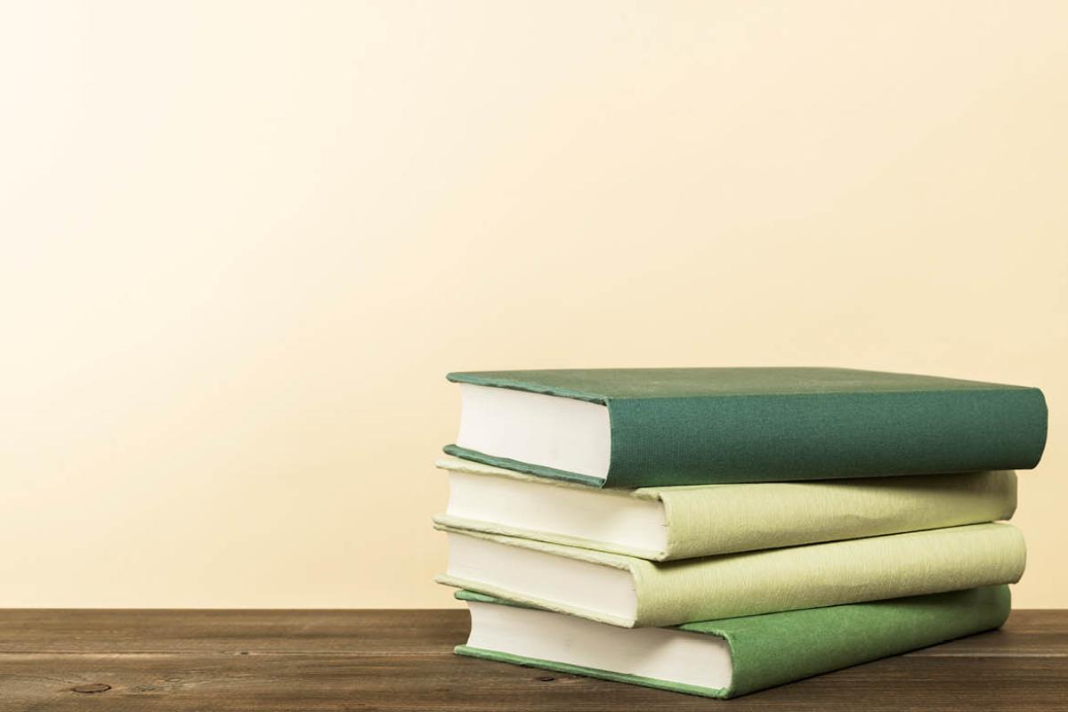 Stack of green books on wooden table.