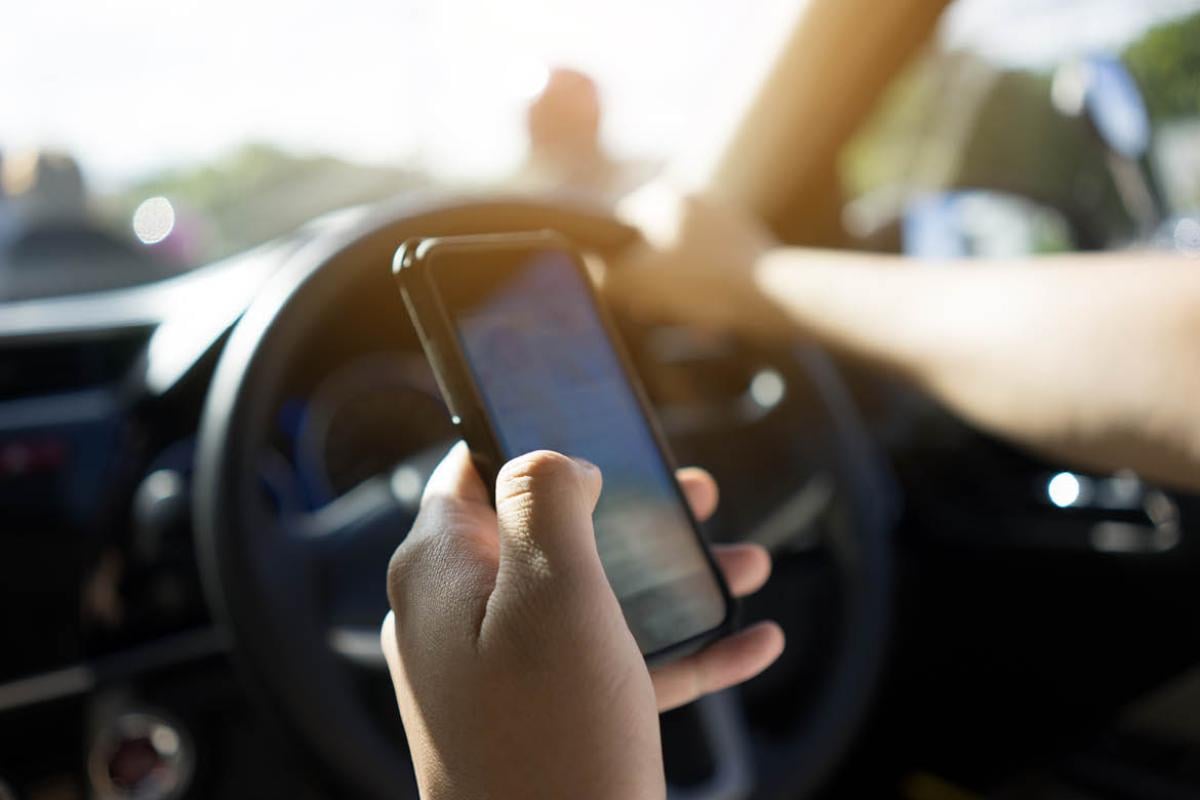 Person driving while holding smartphone
