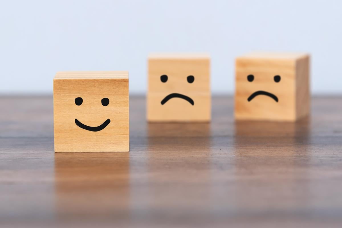 Three wooden blocks with drawn happy and sad faces