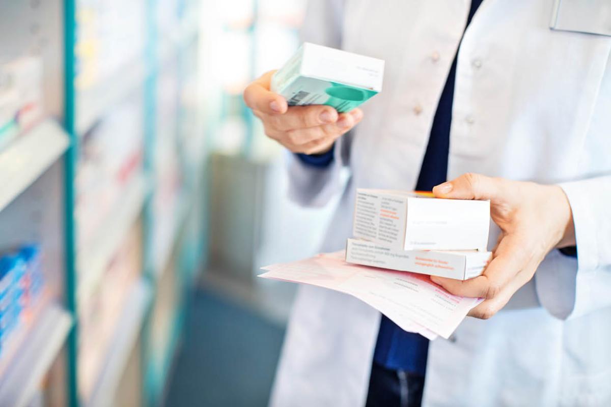 Tight shot of pharmacist reading text on prescription box