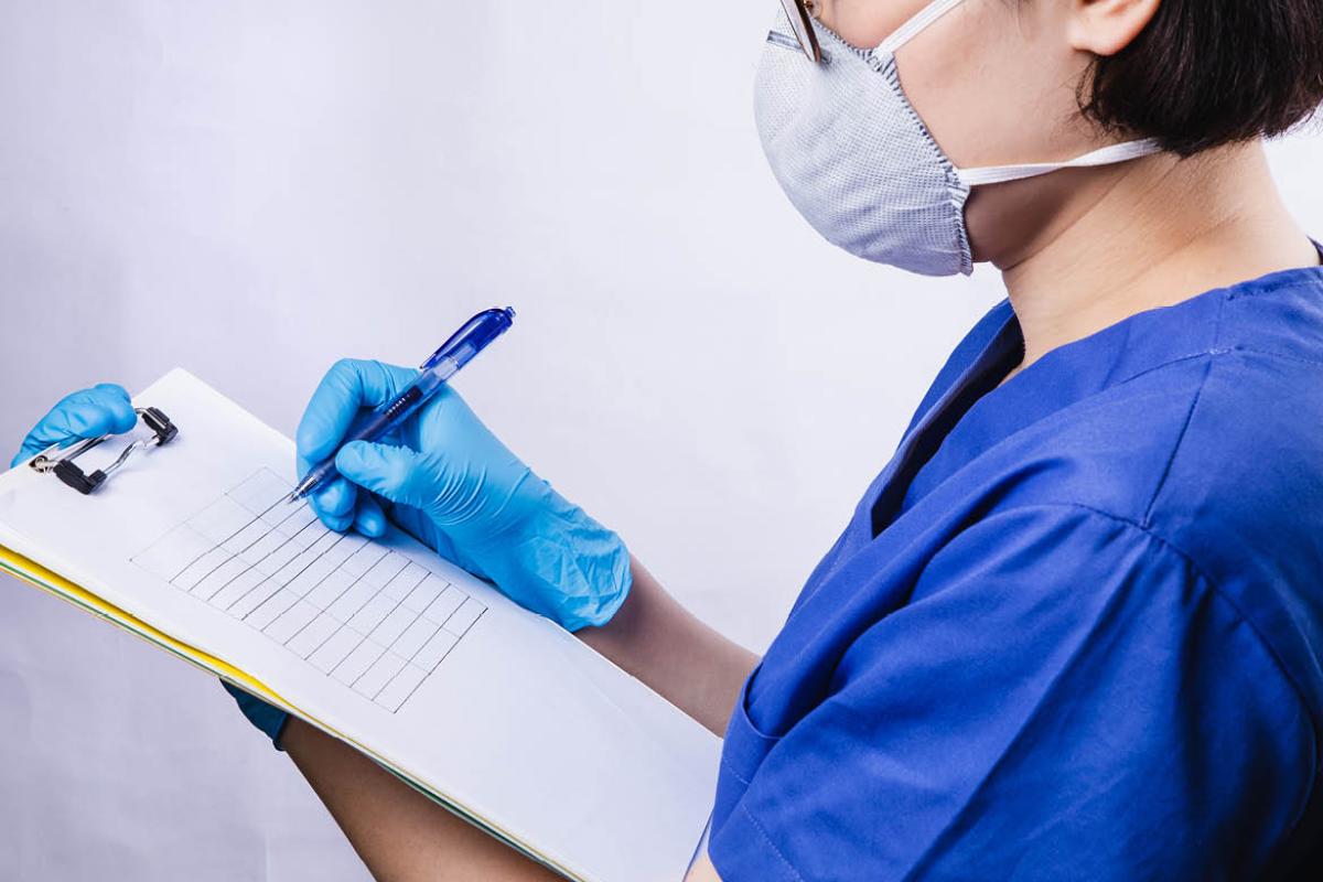 Health care worker writing on a clipboard