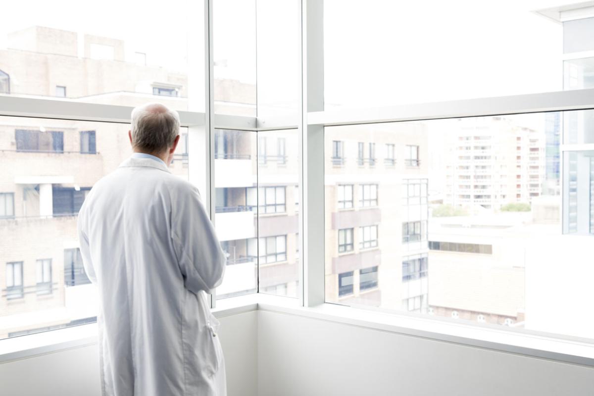 Physician standing alone and looking out a window