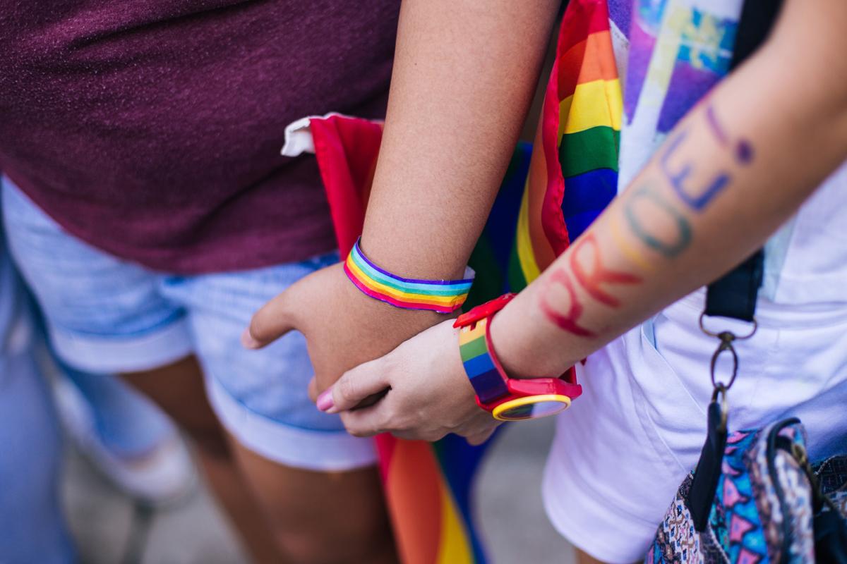 Two people holding hands with the word pride on one person's arm