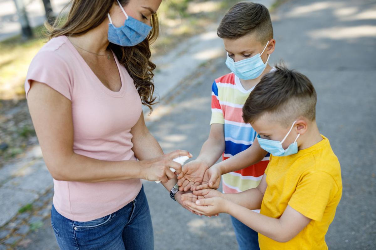Woman and young children using hand sanitizer
