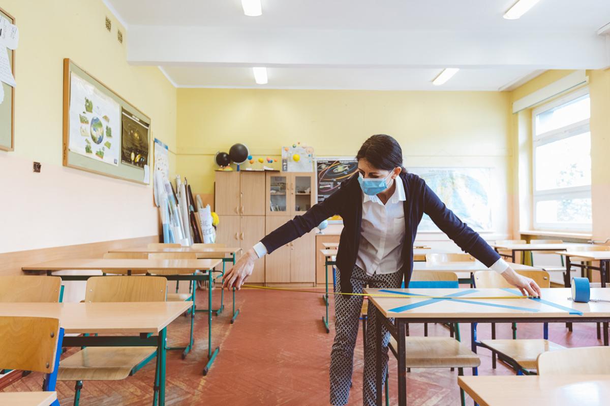 Person in face mask preparing a classroom