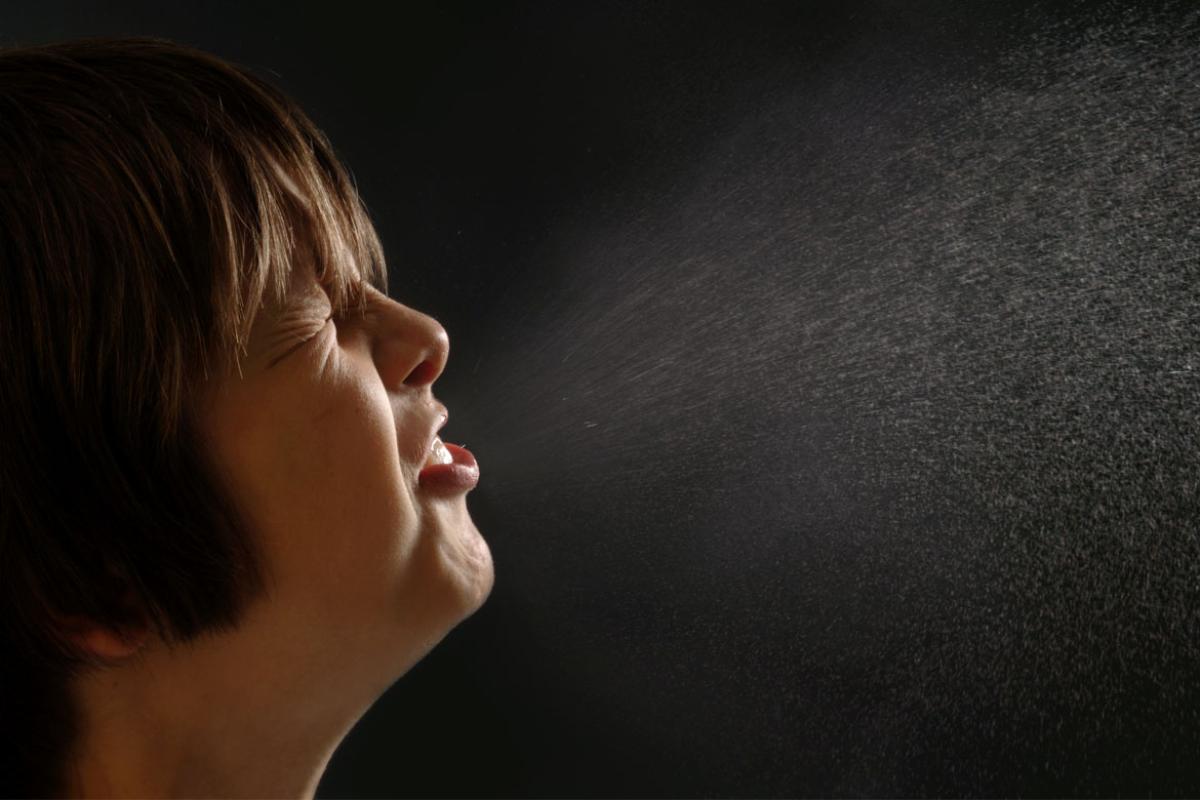 Close up of woman sneezing into the air