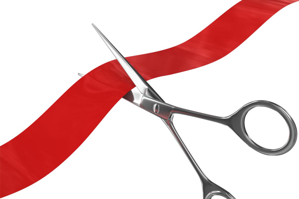 Scissors cutting a red ribbon on a white background
