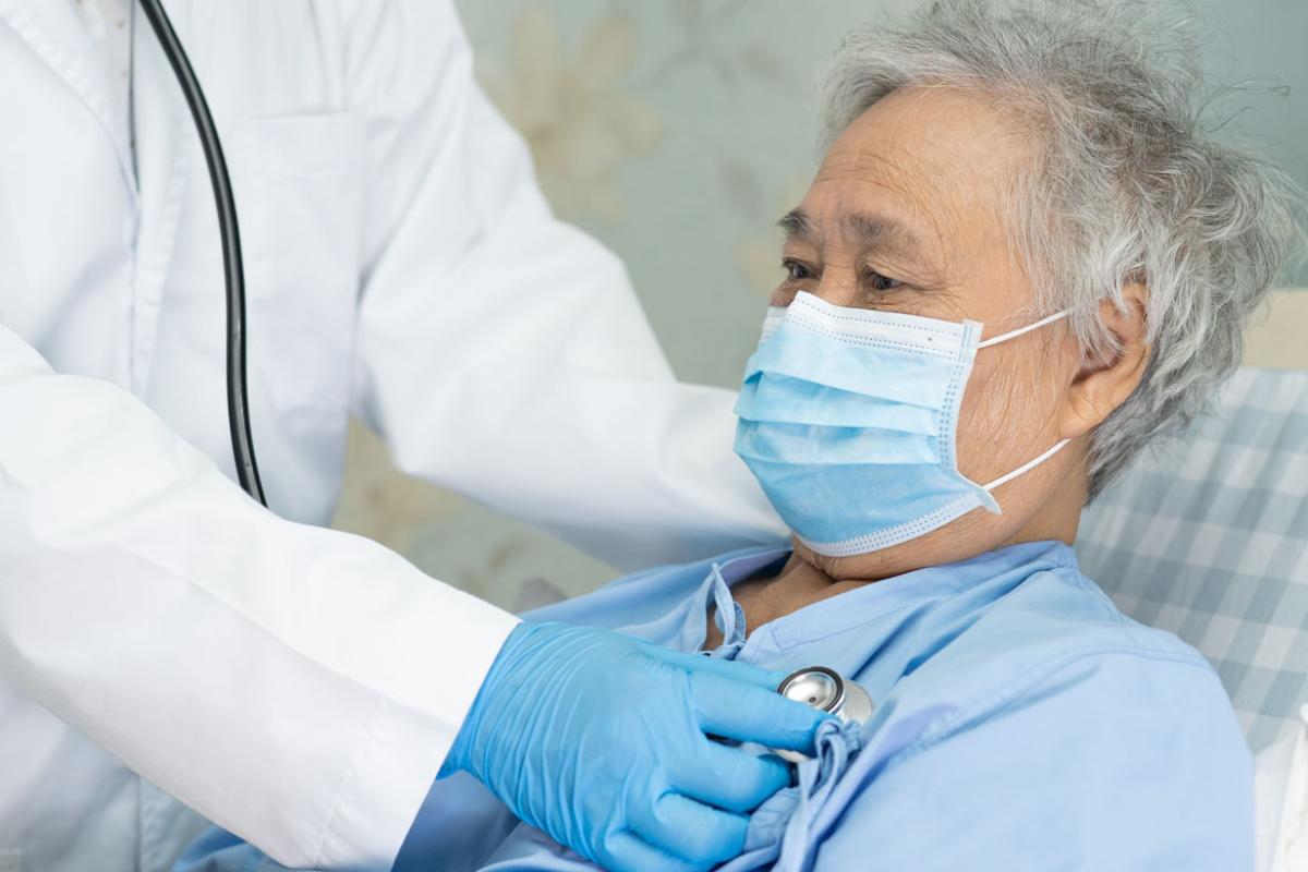 Patient wearing a face mask being examined by physician