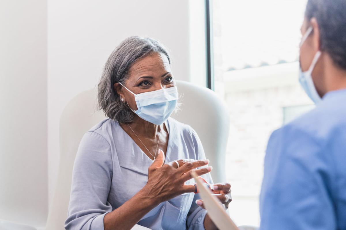 Patient talking to a doctor, both wearing masks.