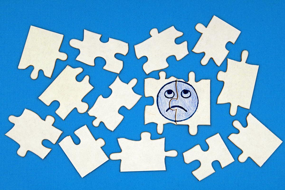 Jigsaw puzzle pieces with sad emoji face.