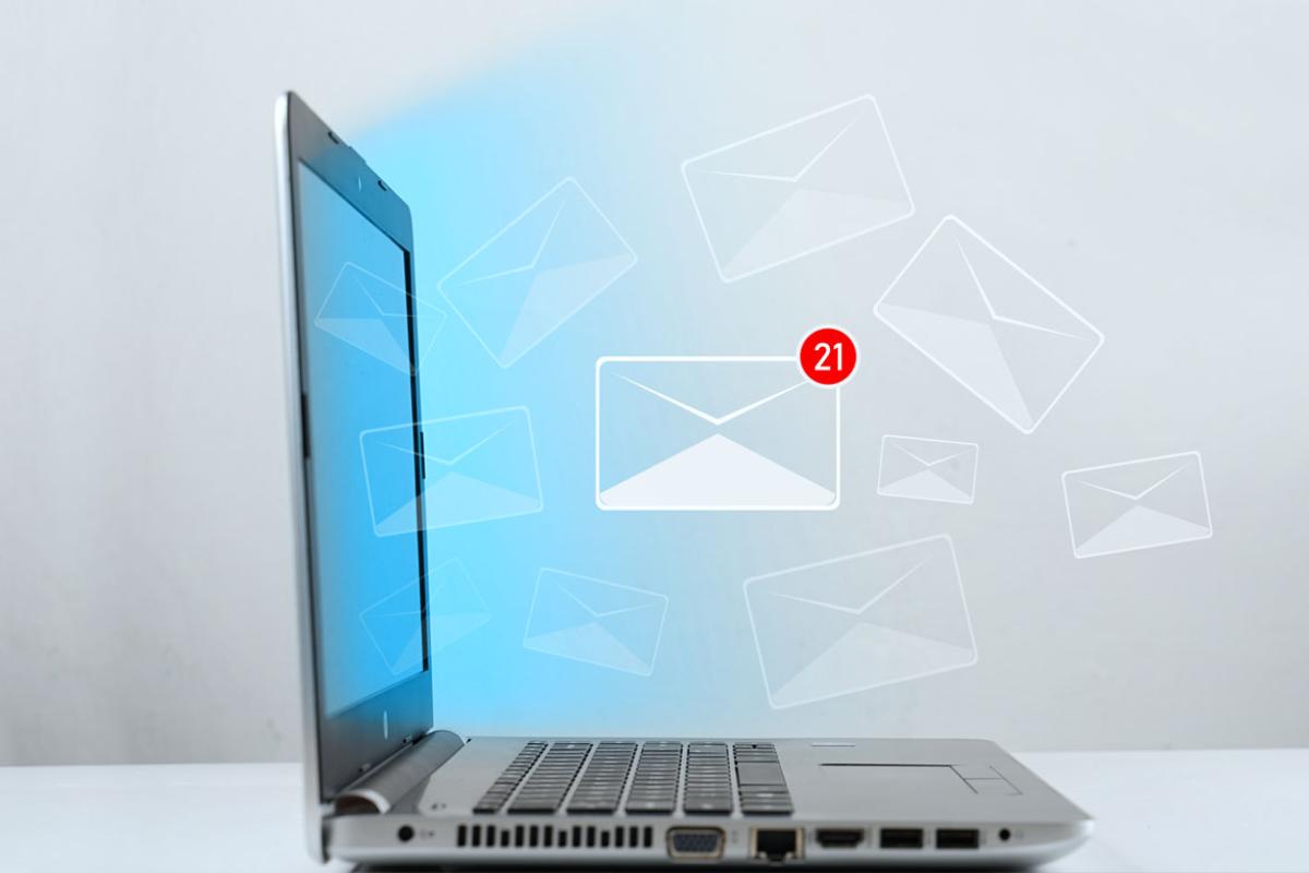 Photo-illustration of an email icon, a white envelop with a red 21 notification, hovering above an open laptop.