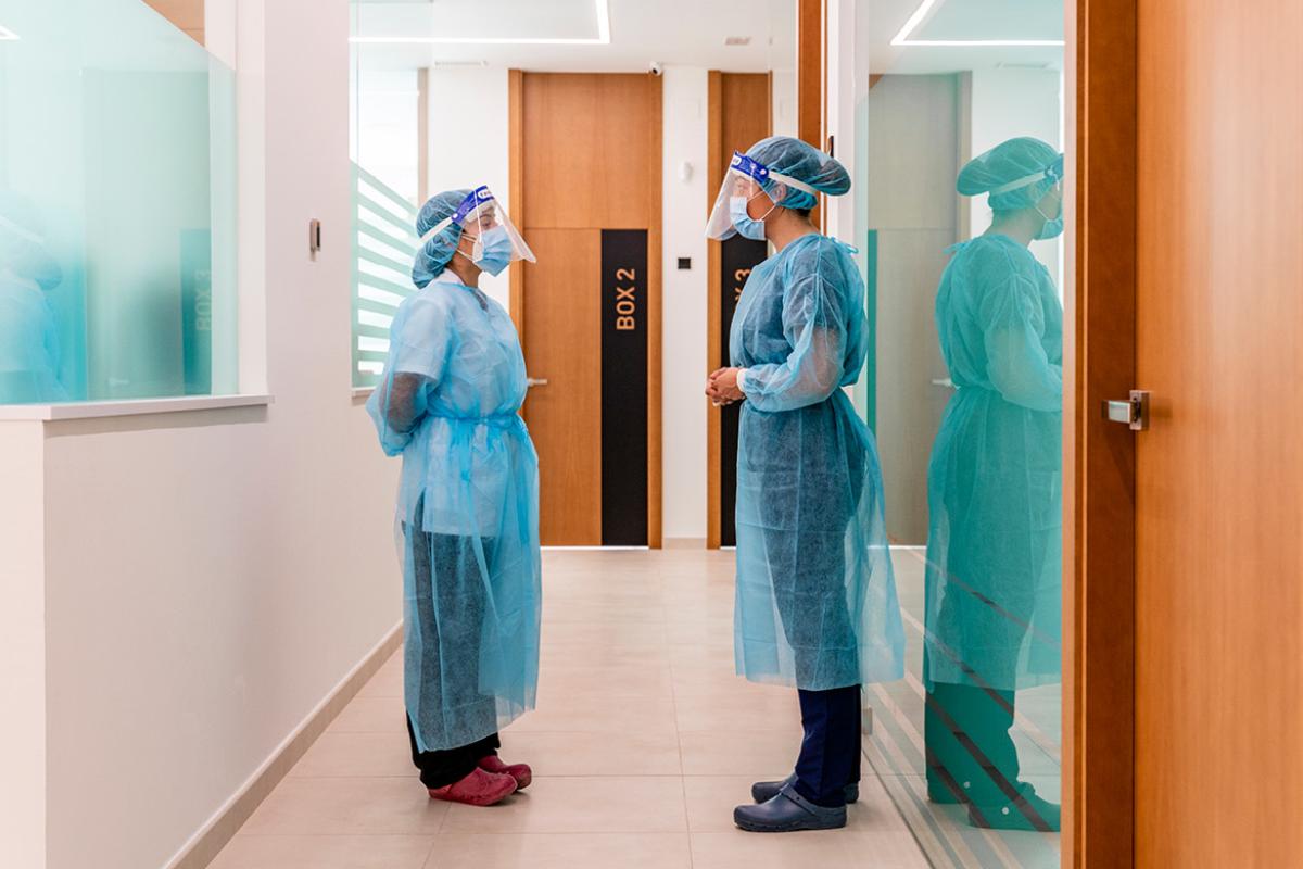 Health care workers in PPE speaking in a hallway