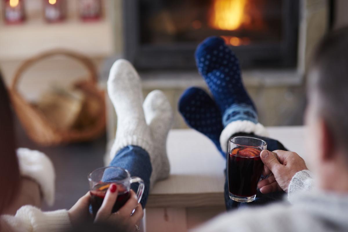 Two people with hot drinks in living room at the fireplace