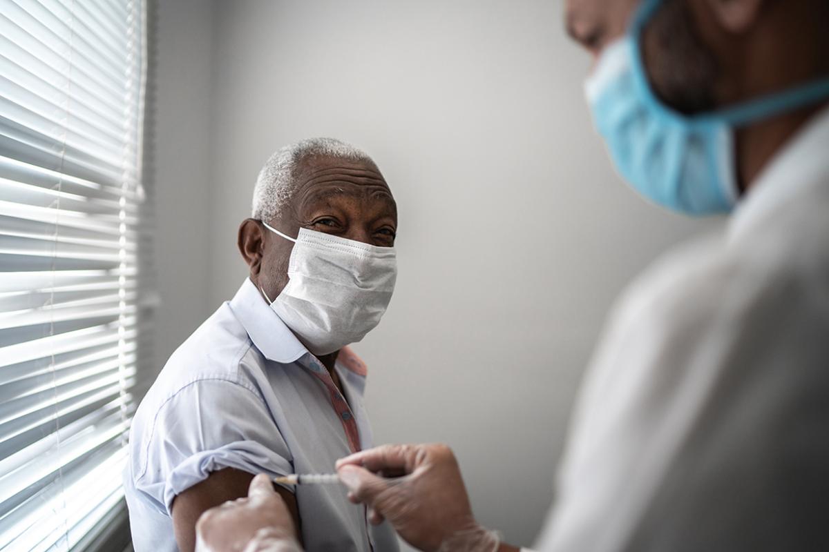 Elderly man receiving vaccine from physician
