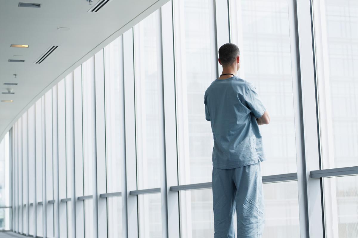 Health care worker looking out a window