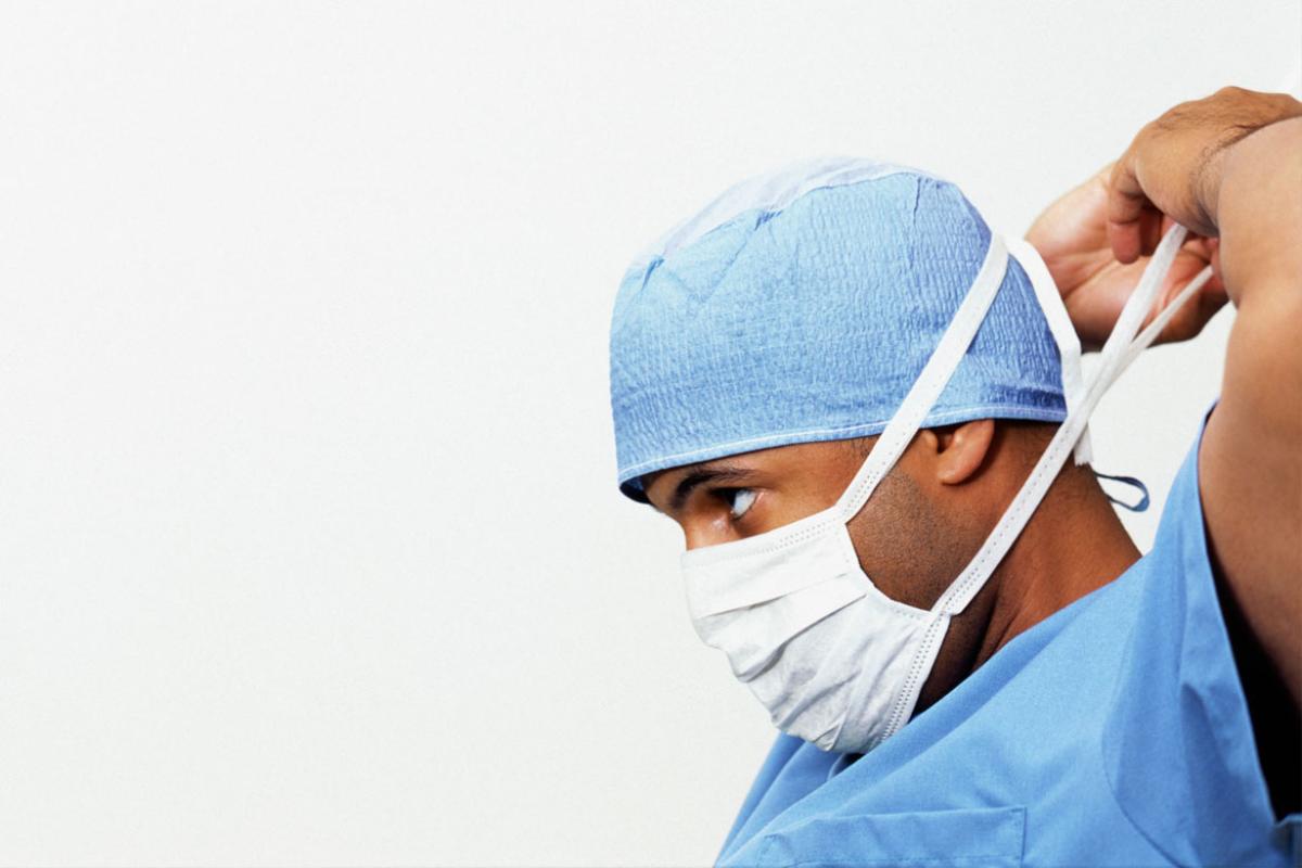 Surgeon putting on surgical mask, side view